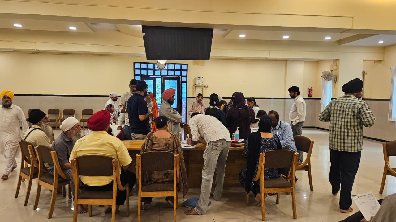 Attendees gathered around medical consultation tables at the Health Checkup Camp in Vapi